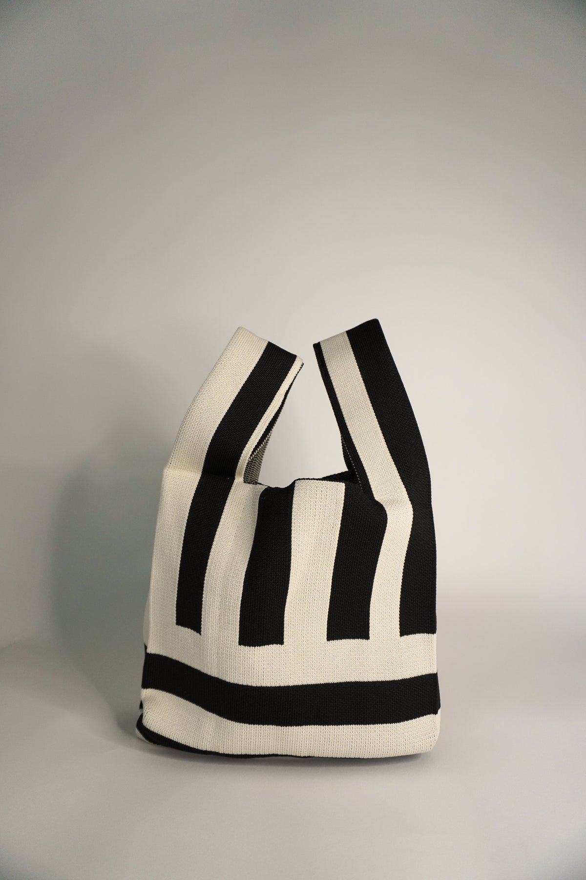 Black and white striped tote bag on a gray background
