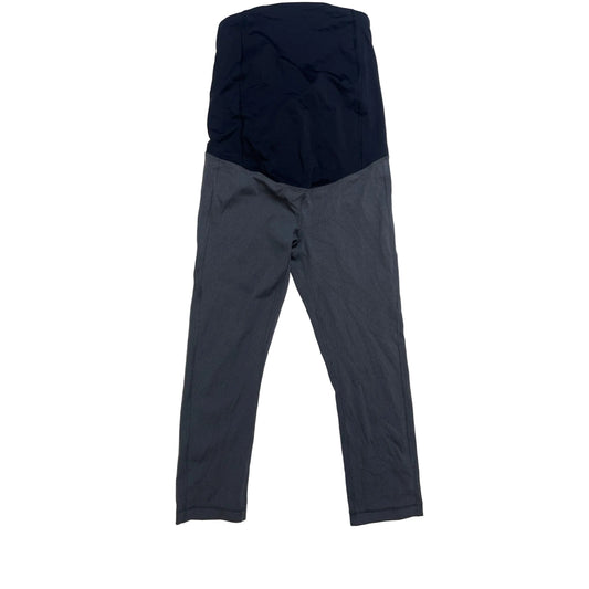 A pair of maternity leggings laid flat on a light beige fabric background. The top section is a solid dark navy blue, and the bottom section is dark gray.